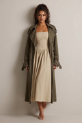 Leaning against a plain studio wall