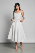 Mid-body – hands on peplum ruffle, looking down